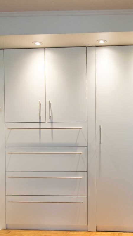 Einbauschrank-Schubladenkombination in Nische mit Dachschräge, ergänzt mit Deckenbeleuchtung.