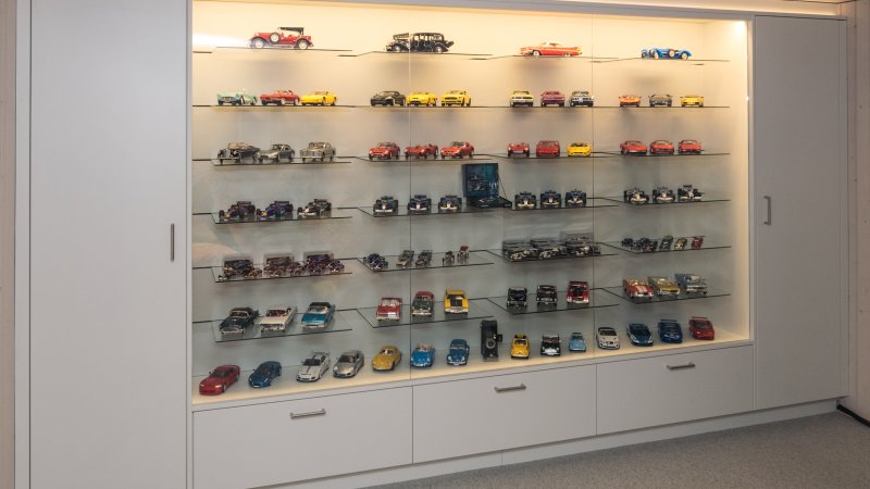 Vitrine mit Einbauschrank kombiniert. Die Seitenschränke und Schubladen geben Stauraum. In der Vitrine kommen die Sammlerobjekte schön zur Geltung und können mit dimmbaren Licht ausgeleuchtet werden. Eine Kombination aus beschichteten Spanplatten, Glas und Licht.